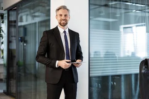 Smiling handsome businessman manager standing in office with tablet computer Foto stock