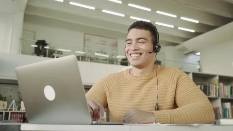Smiling handsome latinos man communicates via video link with a headset on his Stock Footage 143028342