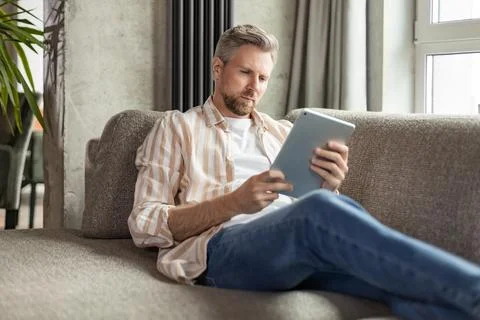 Smiling handsome man using tablet with social networks at home, happy freel.. Stock Photos