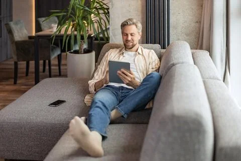 Smiling handsome man using tablet with social networks at home, happy freel.. Foto stock