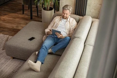 Smiling handsome man using tablet with social networks at home, happy freel.. Stock Photos