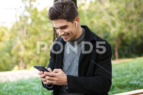 Smiling handsome young cheerful man in casual clothing walking outdoors in gr Stock Photos