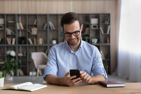 Smiling handsome young man using cellphone applications. Foto stock