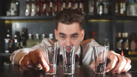 Smiling happy bartender puts the shot glass for vodka Video stock 104536267