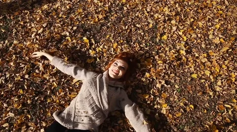 Smiling happy girl portrait, lying in autumn leaves. Outdoor Stock Footage