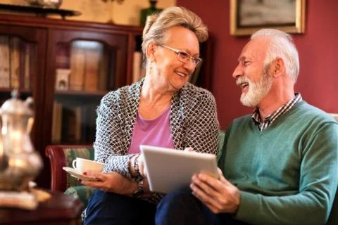 Smiling happy senior friend using tablet and having fun Stock Photos