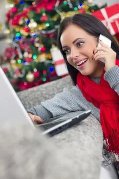 Smiling happy woman using using laptop and cell phone on Christmas night Stock Photos