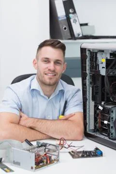 Smiling hardware professional sitting by an open cpu Stock Photos