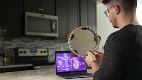 Smiling hipster young man learns to play music on riq or tambourine remote Video stock 168947118