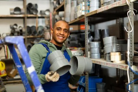 Smiling hispanic foreman looking for PVC pipes in building hypermarket Fotos de archivo