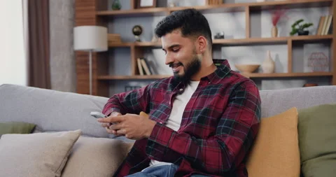 Smiling hispanic man checking social media app playing game, shopping online Stock Footage 225537242