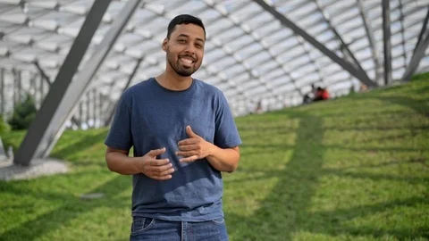 Smiling hispanic man dancing on a green lawn on sunny day 스톡 동영상 96996050
