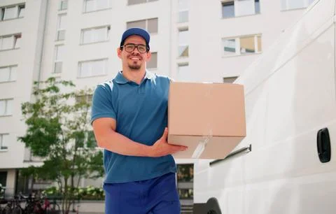Smiling Hispanic Man Delivering Parcel From Courier Service Truck Today. 스톡 사진