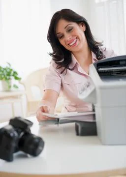 Smiling hispanic woman using printer Stock Photos