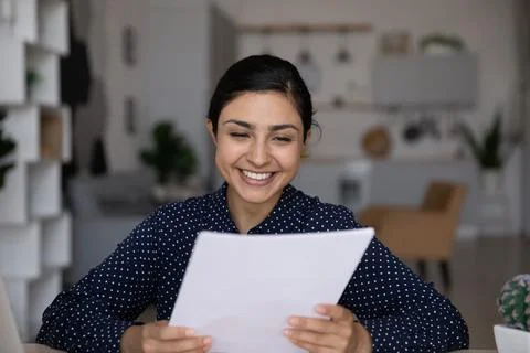 Smiling Indian businesswoman reading good news in letter, holding document Stock Photos