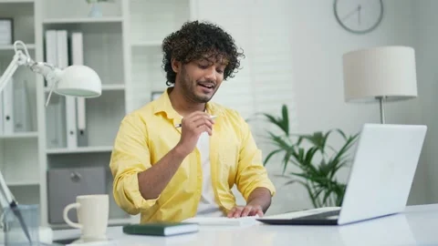 Smiling indian male student elearning study with online tutor teacher talk  Stock Footage 235482580