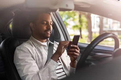 Smiling indian man in car using smartphone Stock Photos
