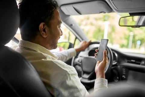 Smiling indian man in car using smartphone Stock Photos