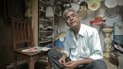 A smiling Indian old man sitting in his roadside small crockery shop Vidéo 85755758