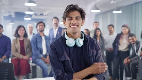 Smiling Indian tech savvy man looking at camera with corporate office employees Stock Footage 246881627