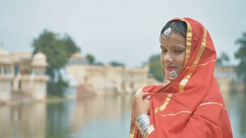 Smiling Indian woman in a traditional cloths looks into a camera beside a lake. Stock Footage