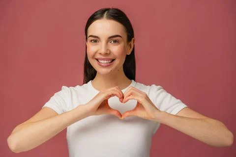 Smiling Individual Gesturing Heart Shape With Hands Against Pink Background Stock Photos