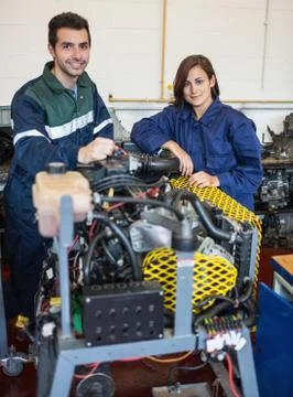 Smiling instructor and trainee standing behind machine Stock Photos