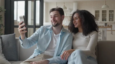 Smiling Interracial Couple Relaxing On Couch Enjoying Happy Video Call At Home Stock Footage 301244997