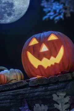 A smiling Jack O Lantern sitting on an old wooden porch with small pumpkins and Foto stock
