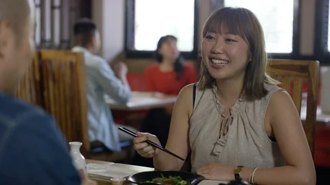 Smiling Japanese couple talking while having meal in restaurant Stock Footage 107954512