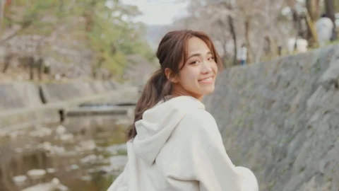 Smiling Japanese runner on river during sakura season Vídeo Stock 105643464