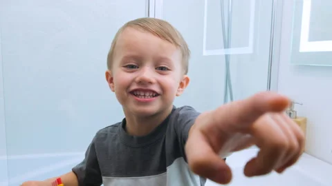 Smiling joyful boy in a gray t-shirt with a toothbrush in his hands pointing Stock Footage 131161391