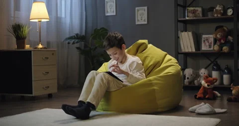 Smiling kid boy playing online game using app on digital tablet in the evening Stock Footage 276483984