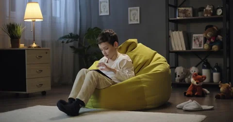Smiling kid boy use digital tablet in the evening, watch streaming service Stock Footage 275559617