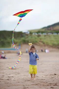 Smiling kid with kite, walking on the beach Stock Photos