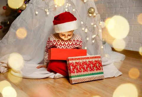 Smiling kid looking inside of glowing Christmas gift box. New Year Fotos de archivo