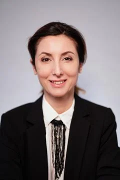 Smiling lady in black jacket posing on gray background looking at camera 库存照片