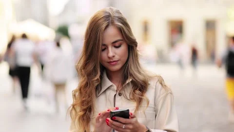 Smiling lady holding cellphone in hands outside. Portrait of happy blonde woman Stock Footage 145223067