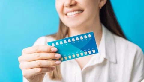 Smiling lady holding a chart of teeth shades Stock Photos