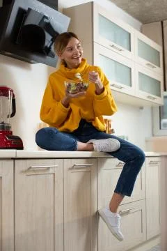 Smiling lady looking away while sitting with bowl of salad Stock Photos