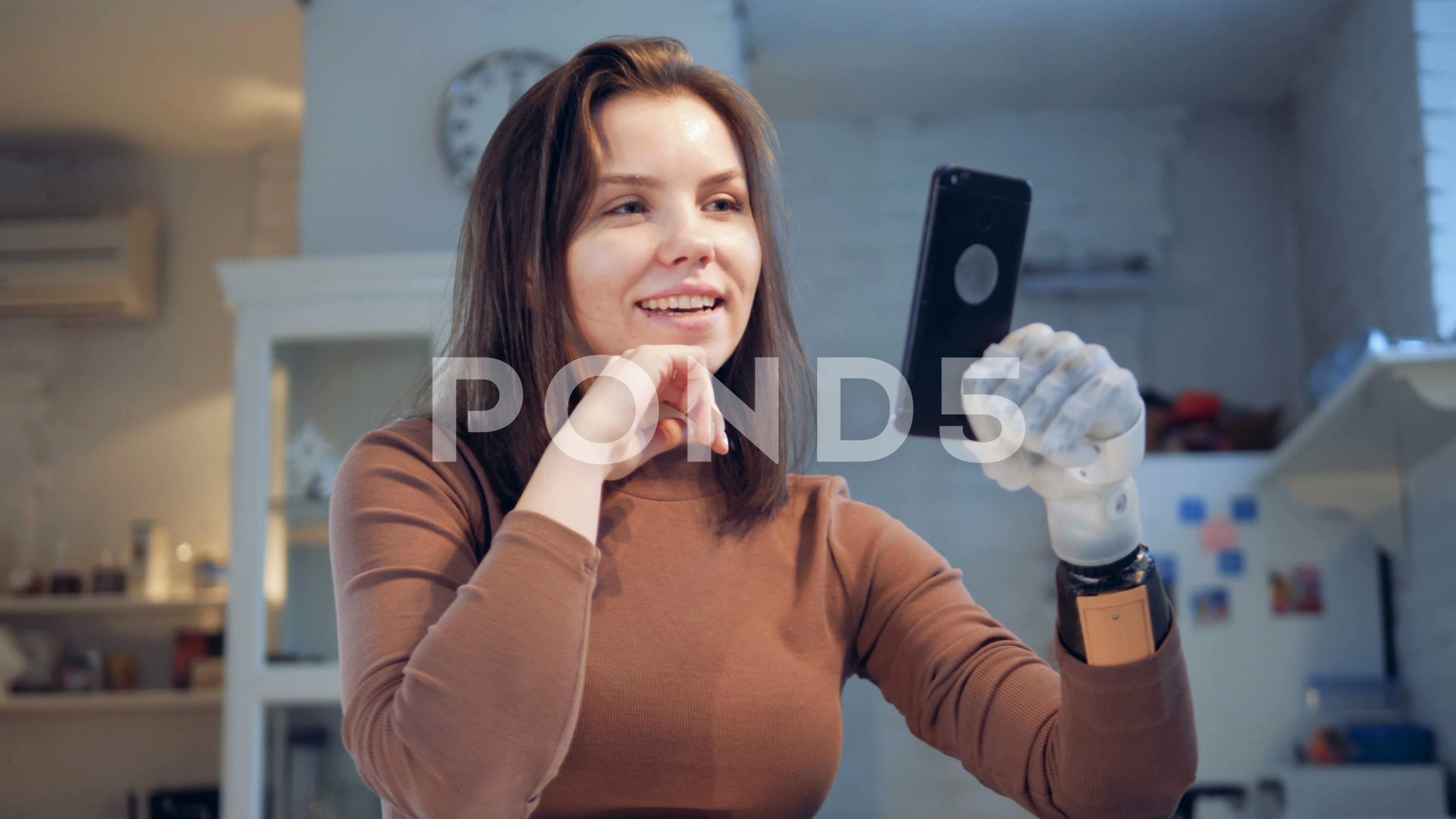 Young woman with prosthetic leg using smart phone by female friend laughing  on sunny day - SuperStock