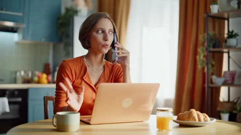 Smiling lady talking mobile phone sitting kitchen desk browsing laptop closeup. Stock Footage 333775862