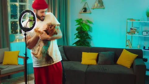 Smiling large charismatic guy influencer playing with his cute dog while make a Video stock 146474366
