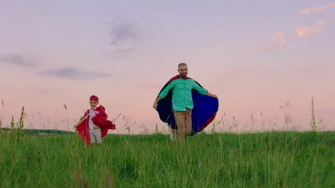 Smiling large man and his cute small son playing together in superheroes they Stock Footage 170010911