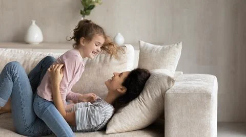 Smiling Latino mother and teen daughter play at home Stock Photos