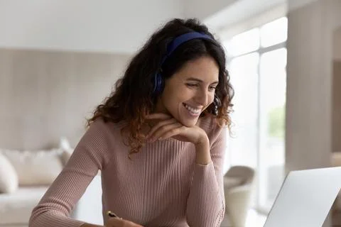 Smiling Latino woman in headphones work on laptop Stock Photos