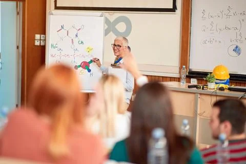 Smiling lecturer in training class with students on university campus. Stock Photos