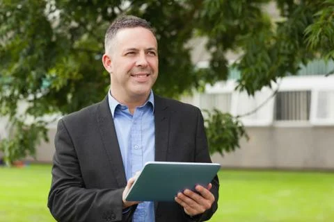 Smiling lecturer using his tablet pc outside on campus Fotos Stock