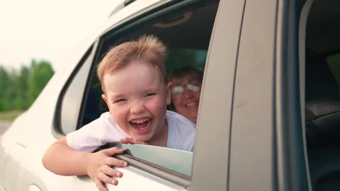 Smiling little boy sits in car with mother looks out window. Child son, smiles Stock Footage 336929346