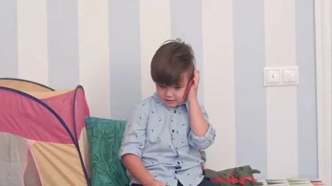 Smiling little boy talking on mobile phone in his room Видео 76583064